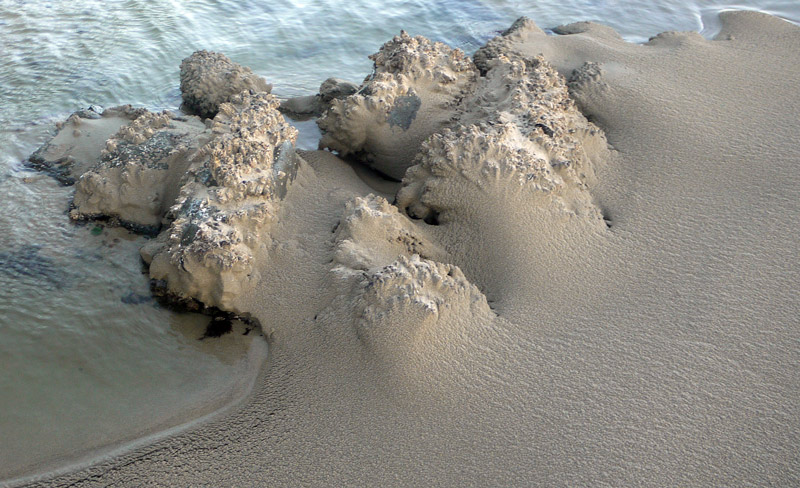 A close shot of the sand blown against rocks, making odd formations.