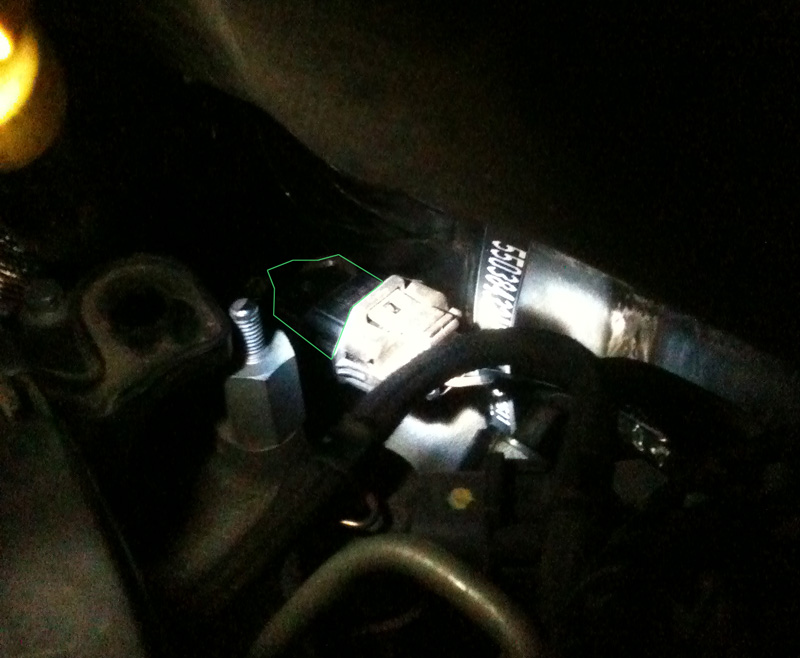 bad photo showing the flashlight illuminated dark hole where the cam sensor (outlined in green) lives on the 2006 Jeep Liberty CRD.